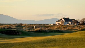 Ein Golfplatz mit einem Haus im Hintergrund.