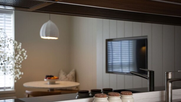 A modern kitchen with a stainless steel faucet, a round dining table, and a pendant light. - Design-led Apartment | Central Pitlochry (Pitlochry)