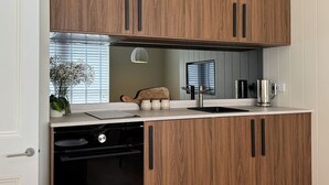 A kitchen with wooden cabinets, a dishwasher, a sink, and a coffee maker. - Design-led Apartment | Central Pitlochry (Pitlochry)