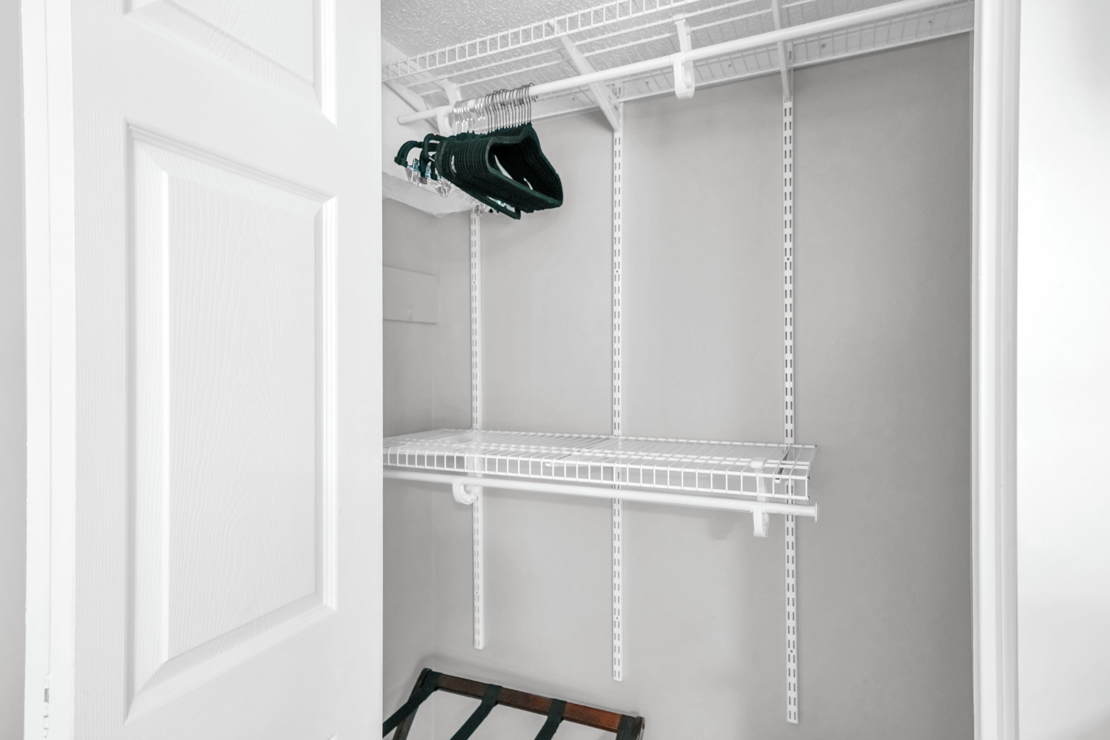 A white closet with metal shelving units and a shoe rack.
