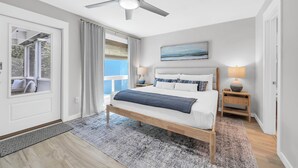 Un dormitorio con cama, ventilador de techo, lámparas de noche y vistas por una puerta.