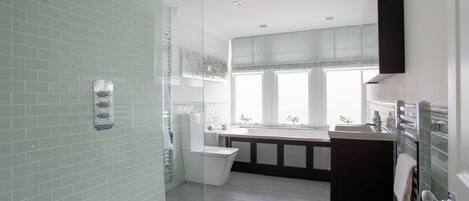 Un baño moderno con cabina de ducha de vidrio, bañera independiente y tocador con espejo.