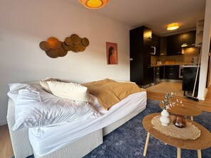 Un salon moderne avec un canapé, une table basse et un coin cuisine à l’arrière-plan.