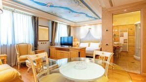 A hotel room with a glass dining table, a TV, a bed with a canopy, and a bathroom with a shower. - Grand Hotel del Parco (Stezzano)