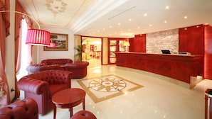 A hotel lobby with a reception desk, plush seating, a patterned floor, and a ceiling with floral designs. - Grand Hotel del Parco (Stezzano)