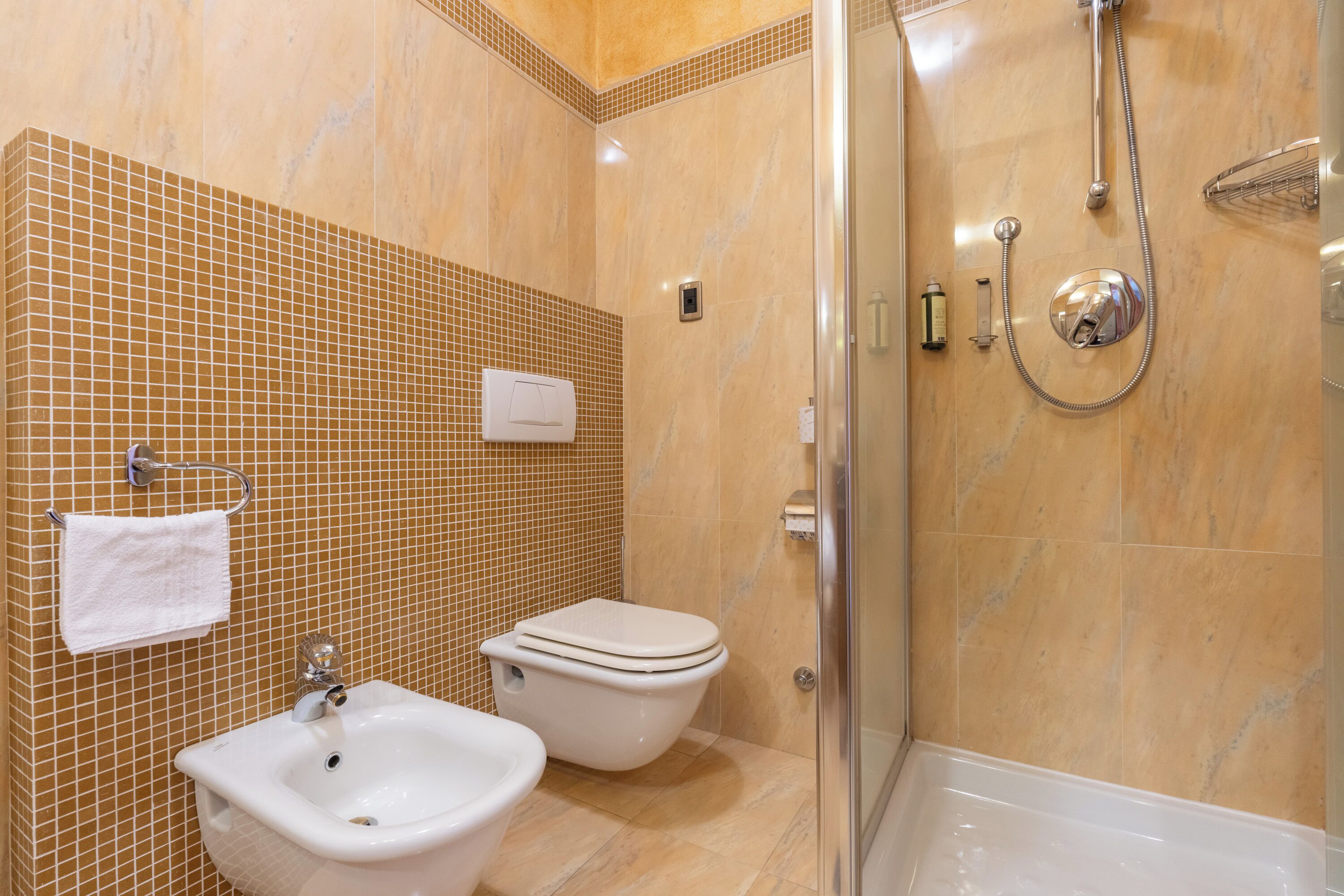 A bathroom with a shower, two sinks, and a toilet.