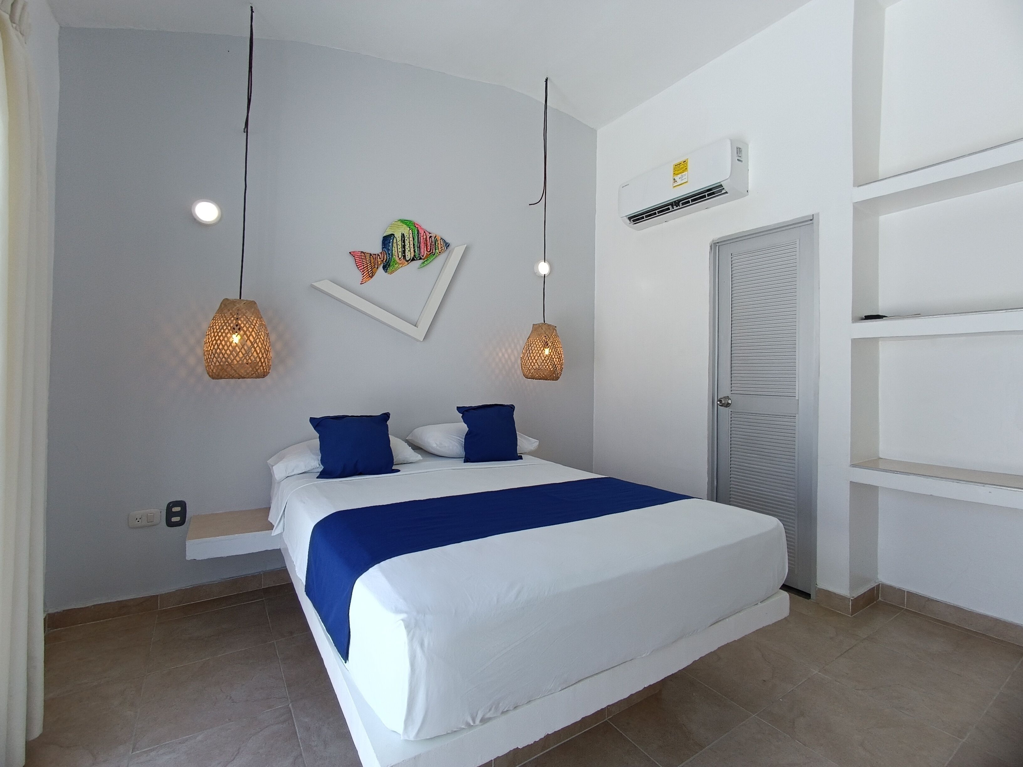 A bedroom with a bed, two wall-mounted lamps, an air conditioning unit, and a door.