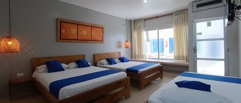 Une chambre d’hôtel avec deux lits, une grande fenêtre avec des rideaux et un climatiseur fixé au mur.