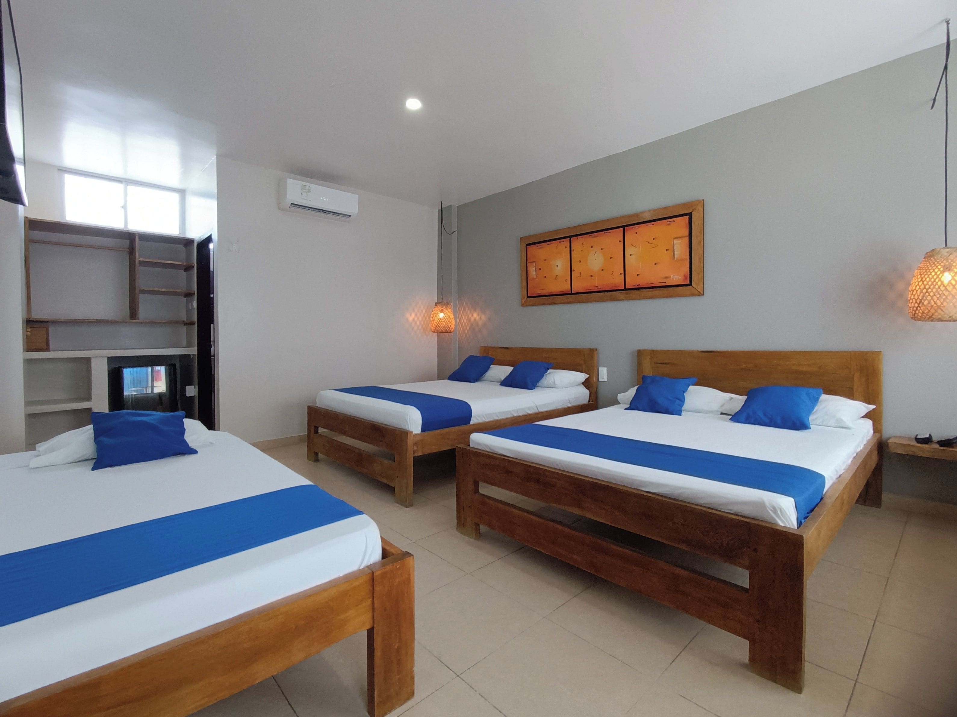 A hotel room with two wooden beds, a wall clock, and a shelf unit.