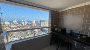 Un balcon avec vue sur la ville, un petit coin cuisine équipé d’un évier et d’un plan de travail, et des murs carrelés.