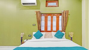Un dormitorio con cama, cortinas, una ventana y aire acondicionado instalado en la pared.