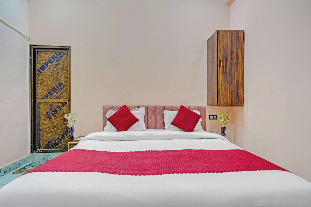 A bedroom with a bed, pillows, a nightstand, a lamp, and a wardrobe.