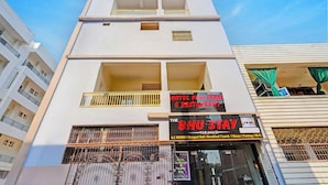 Un edificio de varios pisos con cartel de hotel y restaurante, balcones y entrada protegida por una reja.