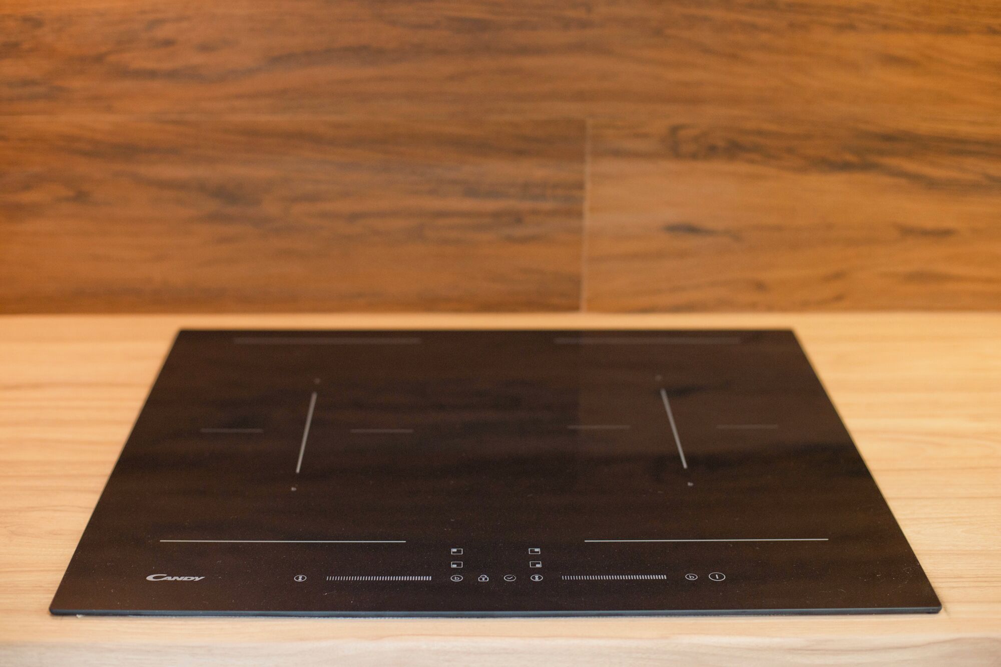 Una cocina por inducción negra con un panel de control y el nombre de la marca 'Candy' en el lado izquierdo.