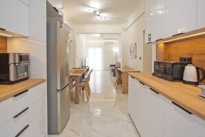 Eine moderne Küche mit Edelstahlgeräten, Holz Arbeitsplatten und einem Marmorboden.