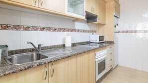 Une cuisine avec des meubles de rangement en bois, un évier en acier inoxydable, un four à micro-ondes et un égouttoir à vaisselle.