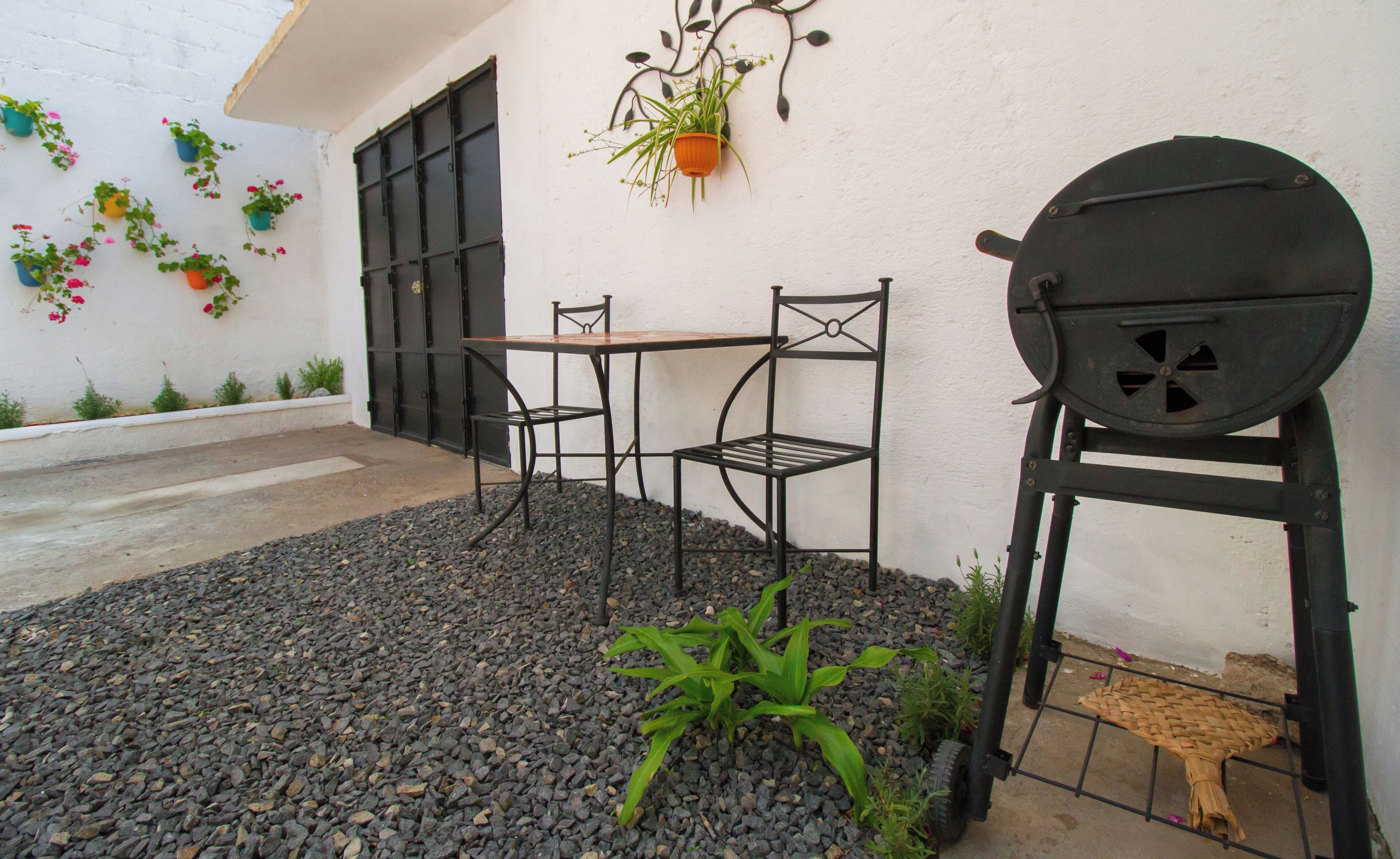 A patio with a table and chairs, a hanging plant, and a barbecue grill.