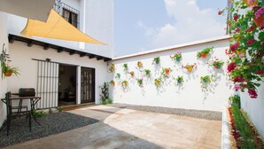 A courtyard with a white wall, potted plants, a yellow canopy, and a concrete floor. -  Casa Cami Anturi (Antigua Guatemala)