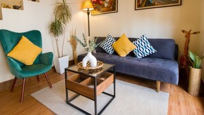 A living room with a green chair, a blue sofa, a wooden coffee table, and two paintings on the wall. -  Casa Cami Anturi (Antigua Guatemala)