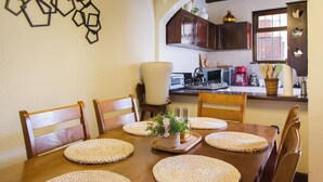 A dining area with a wooden table, chairs, and a kitchen in the background. -  Casa Cami Anturi (Antigua Guatemala)