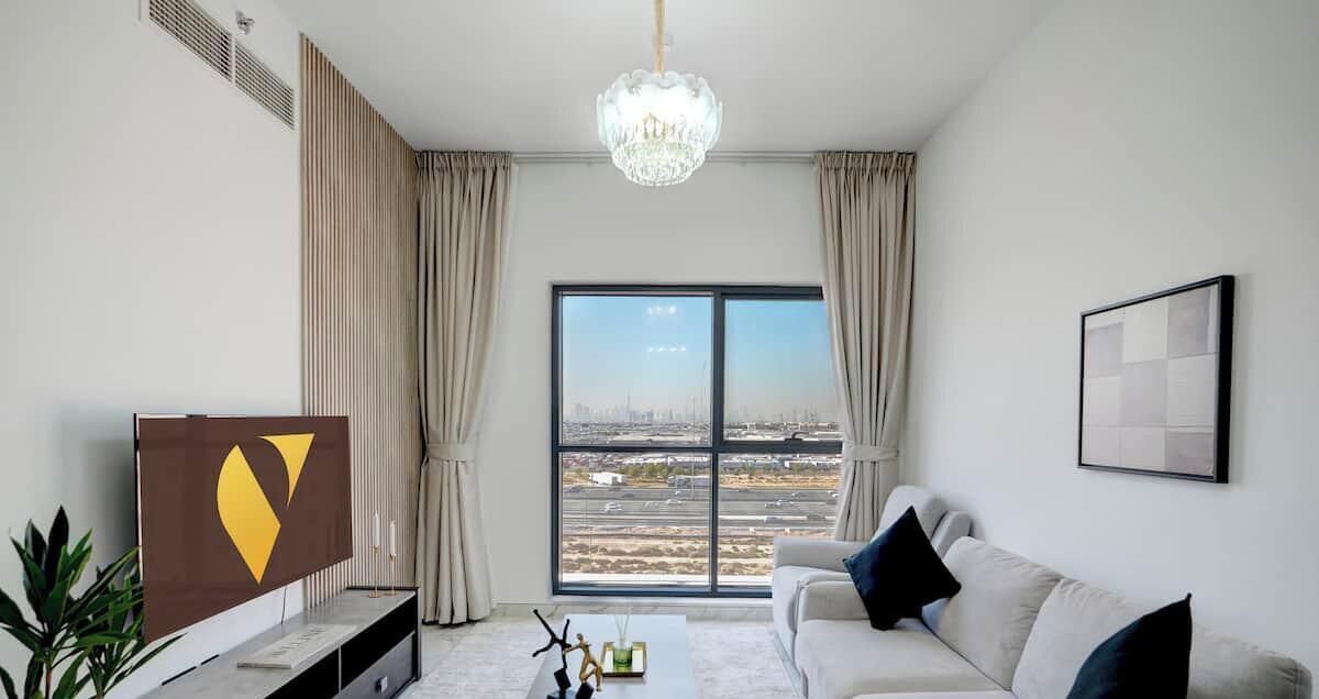 Ein modernes Wohnzimmer mit großem Fenster, einer Kristallleuchtre, einem Sofa und einem Flachbildfernseher.