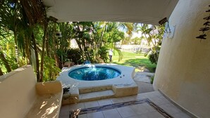Un bain à remous situé dans un espace extérieur abrité, doté d’un sol carrelé et entouré de verdure.