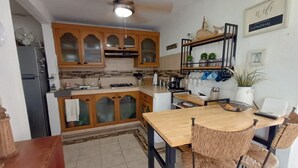 Une cuisine avec des meubles en bois, une table à manger avec des chaises, un ventilateur de plafond et un panneau indiquant la présence d’une connexion Wi-Fi.