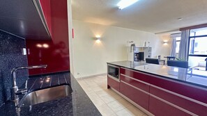 Una cocina moderna con un lavamanos de acero inoxidable, un horno empotrado y una isla grande con microondas.
