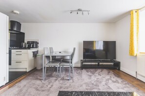 A compact living space with a kitchenette, a dining area, and a flat-screen TV. - Bright 2BDR Apt in Southall with Free Parking (Greater London)