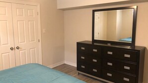 Un dormitorio con cama, cómoda, espejo y puerta.