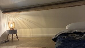 A bedroom with a bed, a bedside lamp, a rug, and a window. - Getaway & Wellness (Ravenel)