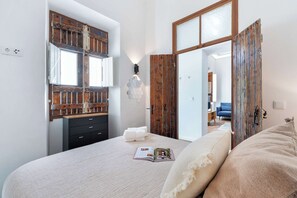 Un dormitorio con cama, cómoda, espejo y puerta que da a otra habitación.