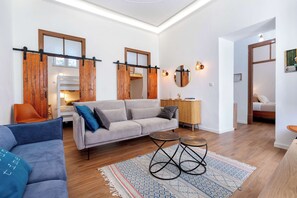 Una sala moderna con sofá, mesa de centro y un ventanal con contraventanas de madera.