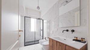 Ein modernes Badezimmer mit einer Glasdusche, einem weißen Waschbecken und einer Holzkommode.