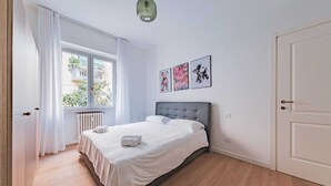 Ein Schlafzimmer mit Bett, Fenster, Heizkörper und Tür.