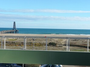 Vista de la playa con un muelle, una valla y cielo despejado.