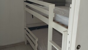 Una cama litera con ventana, una cortina roja y una puerta blanca.