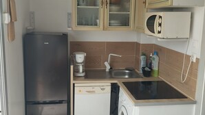 Cocina compacta con refrigerador, lavavajillas, microondas y lavadora.