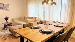 A dining area with a wooden table set for four, a sofa, and a small side table with a vase. - 3BR | parking, WLAN, home office, balcony, view, fully equipped. Kitchen (Bad Mergentheim)