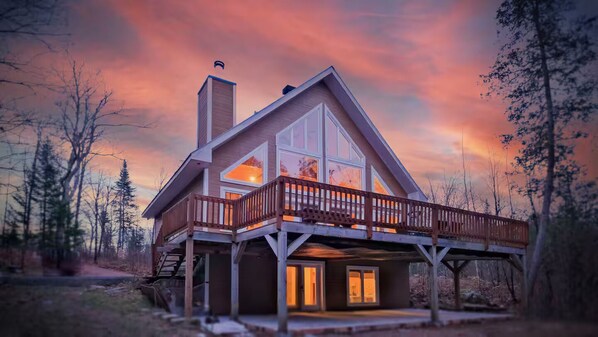 A two-story house with a balcony, a chimney, and a deck.
