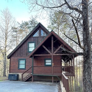 Une cabane en rondins avec un porche, un escalier et une petite terrasse.