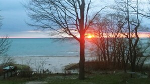 A beach scene with a sunset, trees, and a small structure.