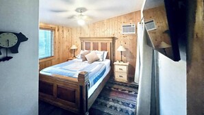 A bedroom with a wooden bed, bedside tables, a clock, and a ceiling fan. - Serene 2-bedroom cabin on The Provo River (Provo)