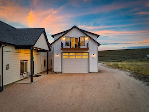 Une maison à deux étages avec un garage, un balcon et une allée gravillonnée.