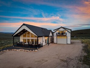 Et toetagers hus med en overdækket terrasse, garage og grusvej.