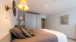 Un dormitorio con cama, lámpara de pared, armario y espejo.