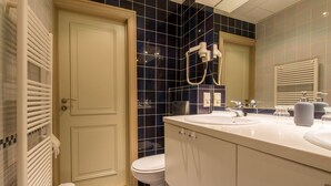 Un baño con inodoro, lavamanos, espejo y toallero.