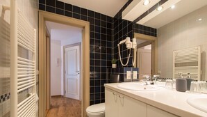 Ein modernes Badezimmer mit zwei Waschbecken, einem großen Spiegel und einer Duschkabine.