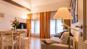 Ein gemütliches Zimmer mit einem Bett, einem Tisch mit Stühlen, einem Fernseher und einer Lampe.
