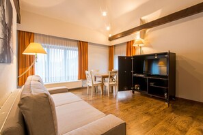 A modern living room with a sofa, a dining table with chairs, a TV stand, and a lamp. - Spacious flat in the historical center w. elevator (Brugge)
